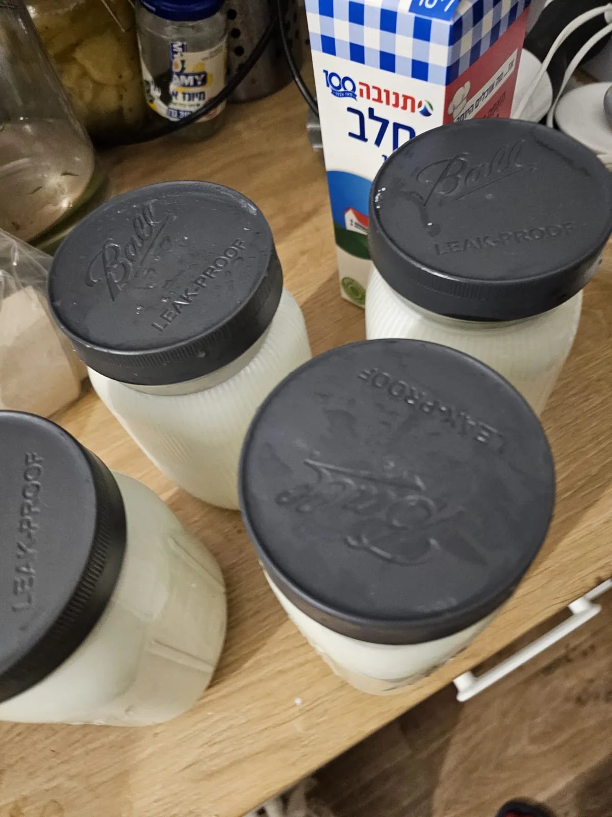 Four wide-mouth Mason jars sealed with black Ball leak-proof lids